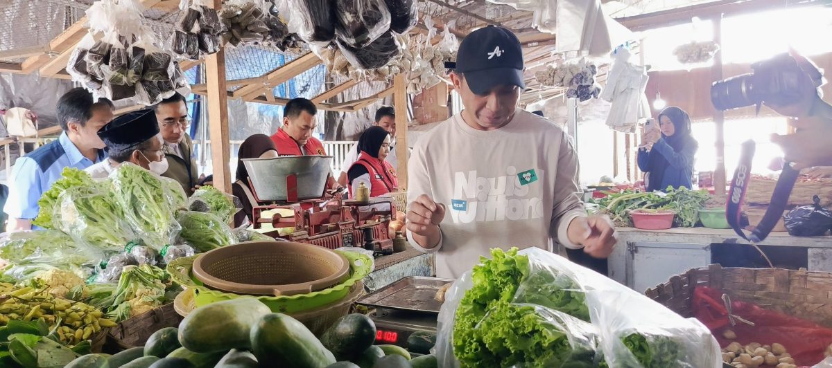 Aiptu Prasetya Wicaksono dari Satgas Pangan Polresta Banyuwangi menanyakan harga cabai dan kebutuhan pokok di lapak bumbu dapur Pasar Banyuwangi saat Ramadan 2026