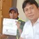 "Seorang petugas pajak sedang memberikan brosur dan penjelasan tentang pembayaran pajak kepada seorang wajib pajak di lapangan."
