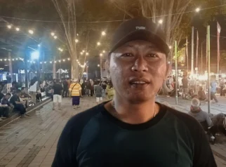 Ketua BHSC Iwan Ho berdiri di depan panggung seni kawasan Taman Blambangan Banyuwangi saat mempromosikan program Jenggirat Tangi Every Week untuk mendukung UMKM dan pariwisata.